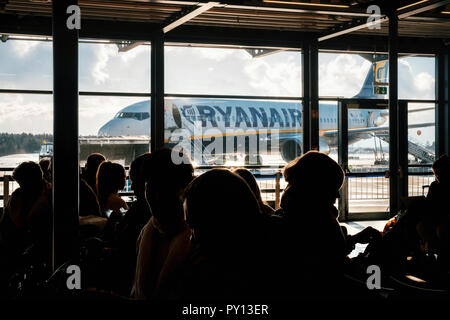 Memmingen, Baviera, Germania - 9 Dicembre 2017: sagome di persone sono in attesa in aeroporto contro aereo Ryanair Foto Stock