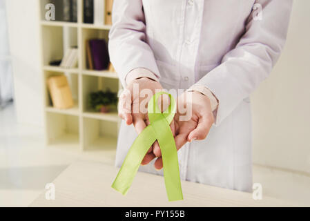 Vista ritagliata del medico tenendo premuto il nastro verde - si celebra la Giornata mondiale della salute mentale Foto Stock