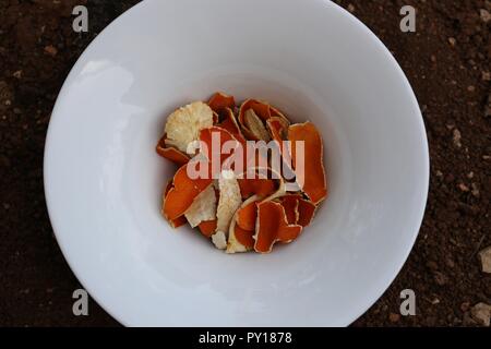 Bucce di mandarino. Home Remedy. Secchi scorze di clementine in ciotola bianco sul terreno. In casa la medicina, l'infusione di essiccato bucce di mandarino, rimedi a base di erbe Foto Stock