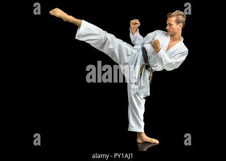 Giovane uomo in bianco kimono karate di formazione. Isolato su sfondo nero. Foto Stock