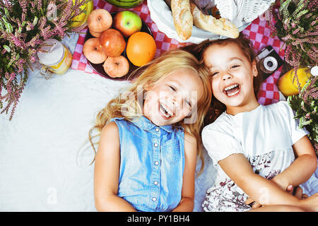 Due bambini allegri giacente su una coperta picnic tra rinfreschi Foto Stock