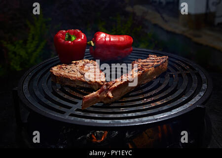 Tomahawk nervatura bistecca di manzo e T-osso su hot grill nero. Foto Stock