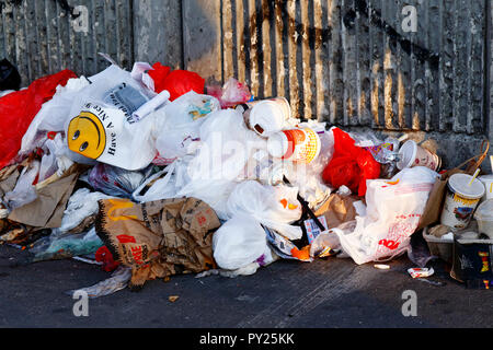 Sacchetti di plastica e rifiuti sparsi su un marciapiede. Foto Stock