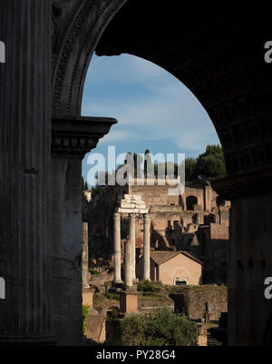 Tre colonne superstiti del Tempio di Castor & Pollux nell'antico foro romano, visto attraverso l'Arco di Settimio Severo. Foto Stock