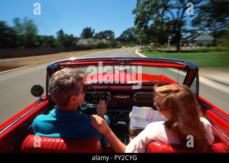 Coppia godendo 1966 Mustang convertibile e leggendo una carta mappa, Stati Uniti Foto Stock
