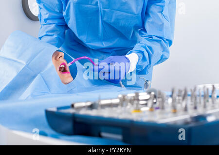 Dentista in uniforme blu di eseguire chirurgia di impianto dentale Foto Stock