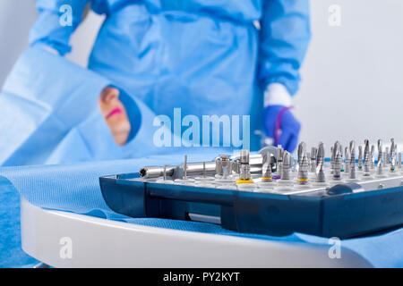 Dentista in uniforme blu di eseguire chirurgia di impianto dentale Foto Stock