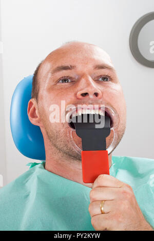 Chiudere l immagine del dentista per scattare delle foto del maschio cavo orale del paziente Foto Stock