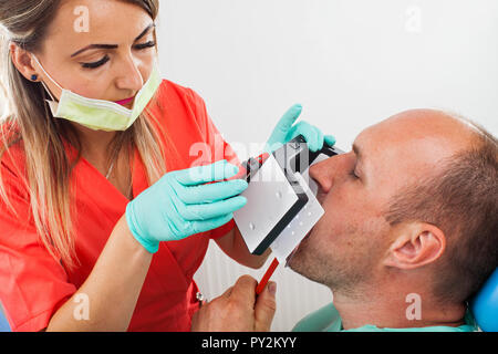 Chiudere l immagine del dentista per scattare delle foto del maschio cavo orale del paziente Foto Stock