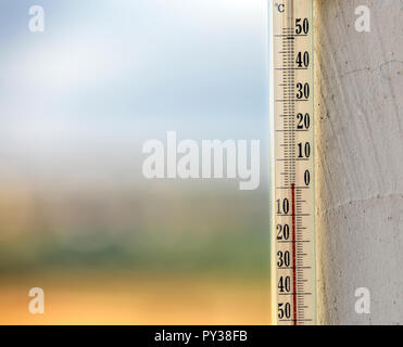 Alcool tradizionale termometro di vetro Celsius attaccata alla parete intonacata al di fuori che mostra la temperatura fredda sulla luminosa luce sfocata colorato all'aperto co Foto Stock