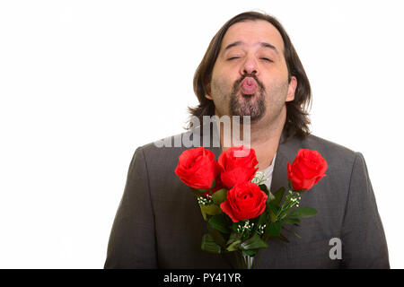 Grasso imprenditore caucasico raggrinzamenti labbra tenendo rose rosse Foto Stock