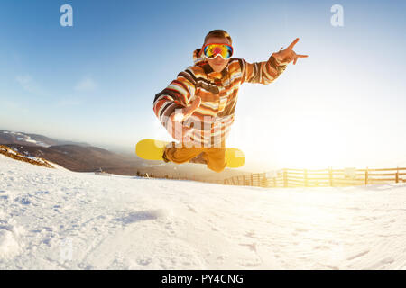 Snowboarder si diverte a salti e caduta in corrispondenza della pista da sci al giocoso pongono Foto Stock