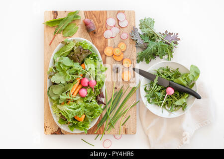 Una scena di prodotti freschi ingredienti su una tavola di legno blocco di taglio in una cucina. Foto Stock