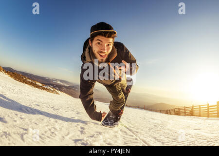 Giovane snowboarder salti e rende giocoso trucco Foto Stock