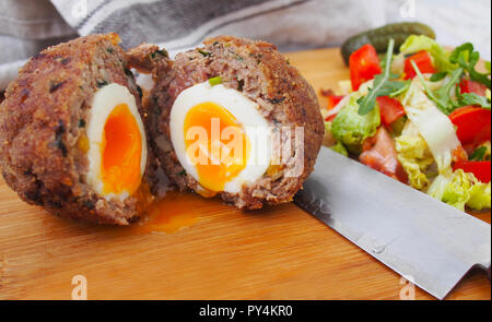 Tradizionale "cotch uovo' su una lastra di legno. Scotch uova e insalata mista Foto Stock