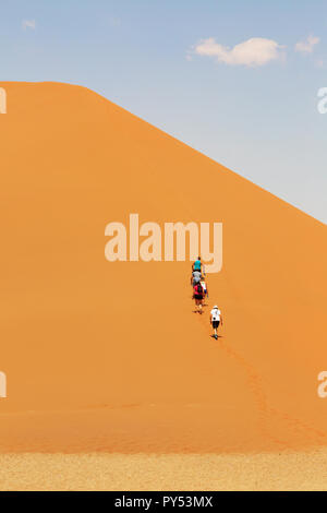 Persone che salgono le dune di sabbia, Sossusvlei, Namib Desert, Namibia Africa Foto Stock