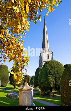 Painswick St Mary's chiesa parrocchiale con colori autunnali albero nel pomeriggio di sole, Painswick, Cotswolds, Gloucestershire, England, Regno Unito Foto Stock