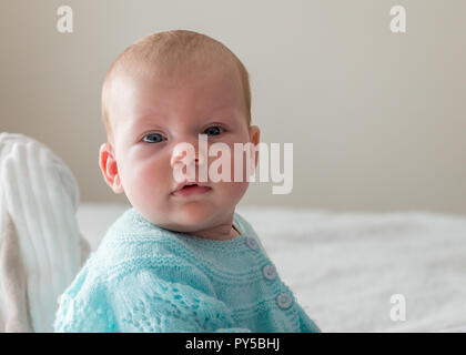 Piccolo bambino seduto sul letto e guardando la telecamera fino in prossimità della faccia verticale. Foto Stock