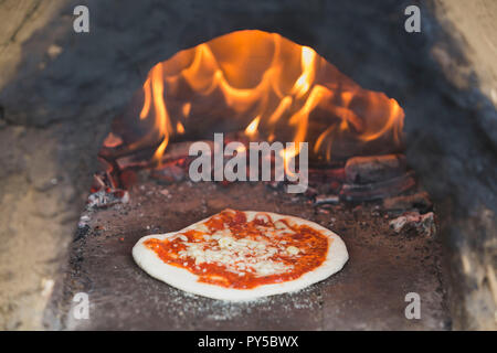 Pizza artigianali essendo cotti su una fatta in casa pizza all'aperto oltre a Bristol, Inghilterra, Regno Unito Foto Stock