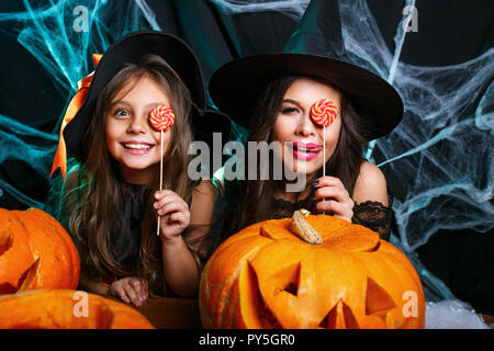 Concetto di Halloween - bella madre caucasica e sua figlia in costumi strega celebrare Halloween con Halloween Candy e dolce su spider web Foto Stock