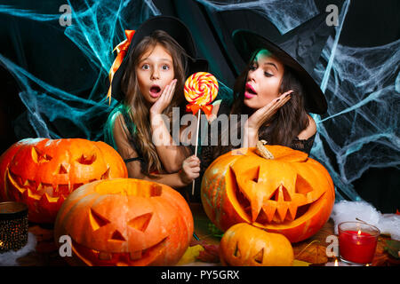 Concetto di Halloween - bella madre caucasica e sua figlia in costumi strega celebrare Halloween con Halloween Candy e dolce su spider web Foto Stock