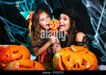 Concetto di Halloween - bella madre caucasica e sua figlia in costumi strega celebrare Halloween con Halloween Candy e dolce su spider web Foto Stock