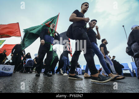 Baghdad in Iraq. 25 ott 2018. Sciita irachena pellegrini fanno la loro strada per la tomba di Imam Hussain durante un giorno di pioggia per eseguire la cerimonia religiosa il quarantesimo giorno dopo la santa sciita giorno di Ashura che commemora la morte di imam Hussein nella battaglia di Karbala. Credito: Ameer Al Mohammedaw/dpa/Alamy Live News Foto Stock