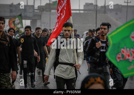 Baghdad in Iraq. 25 ott 2018. Sciita irachena pellegrini fanno la loro strada per la tomba di Imam Hussain durante un giorno di pioggia per eseguire la cerimonia religiosa il quarantesimo giorno dopo la santa sciita giorno di Ashura che commemora la morte di imam Hussein nella battaglia di Karbala. Credito: Ameer Al Mohammedaw/dpa/Alamy Live News Foto Stock