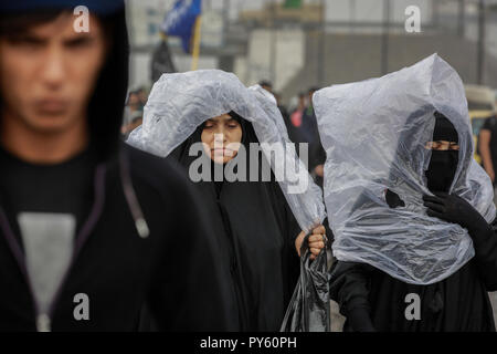 Baghdad in Iraq. 25 ott 2018. Sciita irachena pellegrini fanno la loro strada per la tomba di Imam Hussain durante un giorno di pioggia per eseguire la cerimonia religiosa il quarantesimo giorno dopo la santa sciita giorno di Ashura che commemora la morte di imam Hussein nella battaglia di Karbala. Credito: Ameer Al Mohammedaw/dpa/Alamy Live News Foto Stock