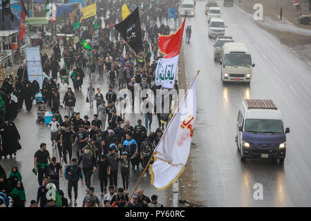 Baghdad in Iraq. 25 ott 2018. Sciita irachena pellegrini fanno la loro strada per la tomba di Imam Hussain durante un giorno di pioggia per eseguire la cerimonia religiosa il quarantesimo giorno dopo la santa sciita giorno di Ashura che commemora la morte di imam Hussein nella battaglia di Karbala. Credito: Ameer Al Mohammedaw/dpa/Alamy Live News Foto Stock
