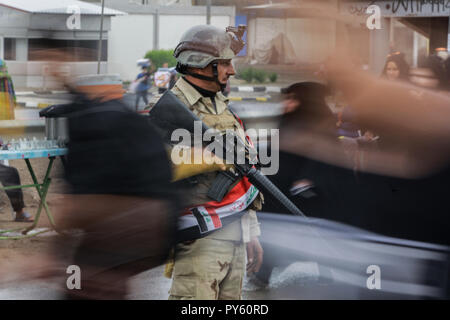 Baghdad in Iraq. 25 ott 2018. Soldati iracheni fissa pellegrini sciiti in cammino verso la tomba di Imam Hussain durante un giorno di pioggia per eseguire la cerimonia religiosa il quarantesimo giorno dopo la santa sciita giorno di Ashura che commemora la morte di imam Hussein nella battaglia di Karbala. Credito: Ameer Al Mohammedaw/dpa/Alamy Live News Foto Stock