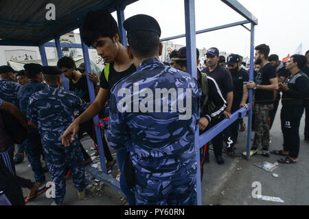 Baghdad in Iraq. 25 ott 2018. Soldati iracheni ispezionare pellegrini sciiti come fanno il loro modo per la tomba di Imam Hussain durante un giorno di pioggia per eseguire la cerimonia religiosa il quarantesimo giorno dopo la santa sciita giorno di Ashura che commemora la morte di imam Hussein nella battaglia di Karbala. Credito: Ameer Al Mohammedaw/dpa/Alamy Live News Foto Stock