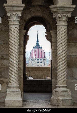 Budapest, Ungheria - Il Parlamento ungherese edificio attraverso un balconcino medioevale con archi e colonne in stile gotico Foto Stock