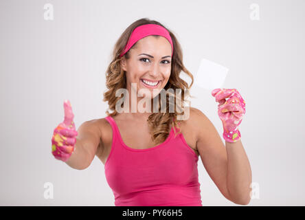 Donna felice nel corredo di pulizia tenendo in mano un pezzo di carta mentre sorridente e guardando la telecamera Foto Stock