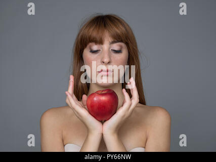 Varie espressione da ragazza giovane con apple frutta fresca su sfondo neutro Foto Stock