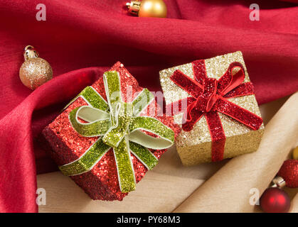 Due confezioni regalo con archi, su red e golden ondulata tessuti di raso con le palle di Natale. Foto Stock