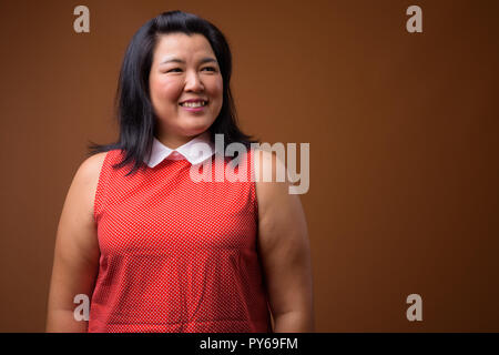 Bellissimo il sovrappeso donna asiatica sorridente e pensare Foto Stock