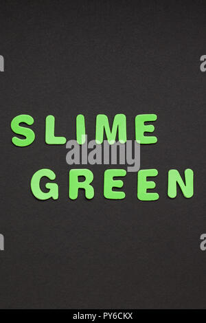 Creative testo colorato in plastica lettere Slime scritta Verde su nero lo sfondo della carta con copia spazio. Colore alla moda concetto blogger template Foto Stock