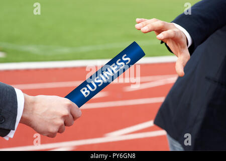 Close-up di due proprietari la mano passando un relè blu testimone a Stadium Foto Stock