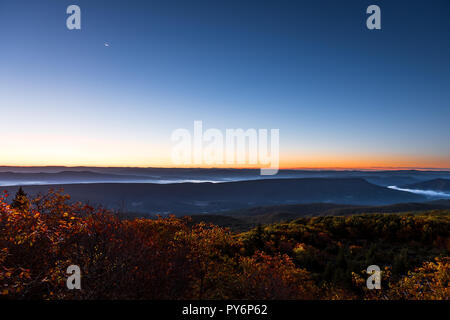 Recare le rocce si affacciano durante il Sunrise, dawn, la luna in autunno con paesaggio roccioso in Dolly zolle, West Virginia Arancio con fogliame degli alberi, blu cielo giallo Foto Stock