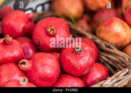 Primo piano di fresche e mature, di colore rosa o rosso melograno frutti arrotondati, pelle, tutta la strada nel mercato agricolo il display bakset in Italia durante il periodo estivo, vibr colorati Foto Stock