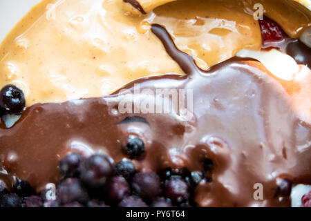 Macro closeup di salsa al cioccolato e burro di arachidi, mirtillo, mirtillo bacche sulla sommità di porridge Foto Stock