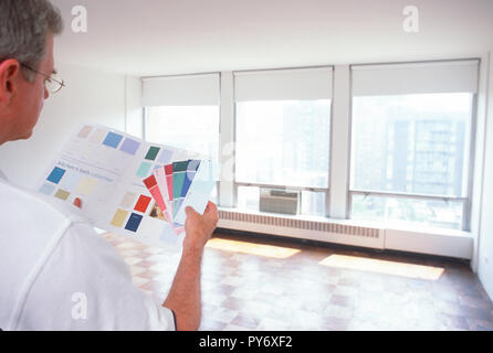 Uomo maturo esaminando campioni di vernice per una New York City apartment, STATI UNITI D'AMERICA Foto Stock