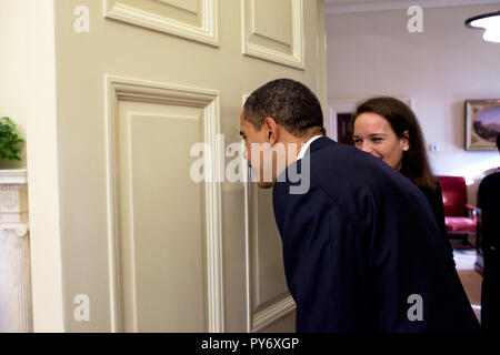 Il presidente Barack Obama guarda attraverso l'Ufficio Ovale porta occhio magico come suo segretario personale Katie Johnson orologi 3/12/09. Gazzetta White House Photo by Pete Souza Foto Stock