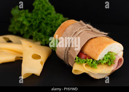 Con sandwich con prosciutto e formaggio, pomodori, lattuga su pietra. Foto Stock