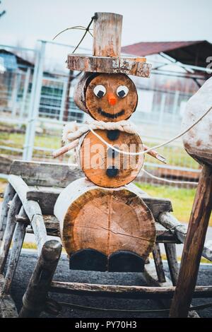 Un bel pupazzo di neve in legno si siede in un nuovo anno di slitta. Gli sled sono raccolte da un cervo. Essi portano il Natale a noi. Foto Stock