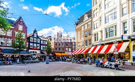 I turisti incontro presso il Spui Plein (piazza Spui) circondato da case storiche ornato di gables nel centro storico di Amsterdam, in Olanda Foto Stock