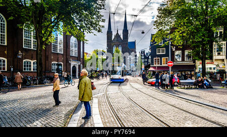 I turisti incontro presso il Spui Plein (piazza Spui) nel centro storico di Amsterdam con la Chiesa Kruitberg in background in Olanda Foto Stock