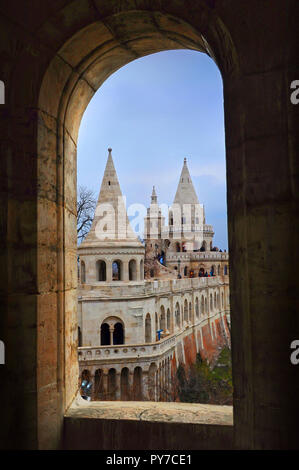 Vista sulle numerose torri del Bastione del Pescatore su una giornata invernale attraverso una finestra ad arco. Budapest. Foto Stock