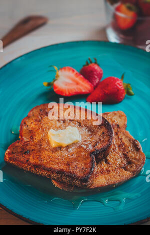 Deliziosi toast alla francese , fragole e sciroppo d'acero su un tavolo di legno Foto Stock